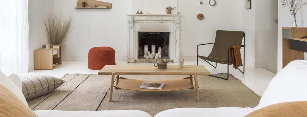 salon lumineux cheminée avec moulure peinte en blanc mobilier bois clair fauteuil d'appoint pouf grand coussin assise confortable style scandinave